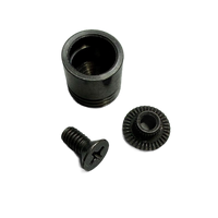 Three small black metal hardware components on a transparent background: a cylindrical sleeve, a threaded screw, and a small ring-shaped gear or clip.
