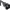 Close-up of a black tactical firearm stock or receiver area with a gloved hand holding a small black accessory or component in front of it, shown on a transparent background.