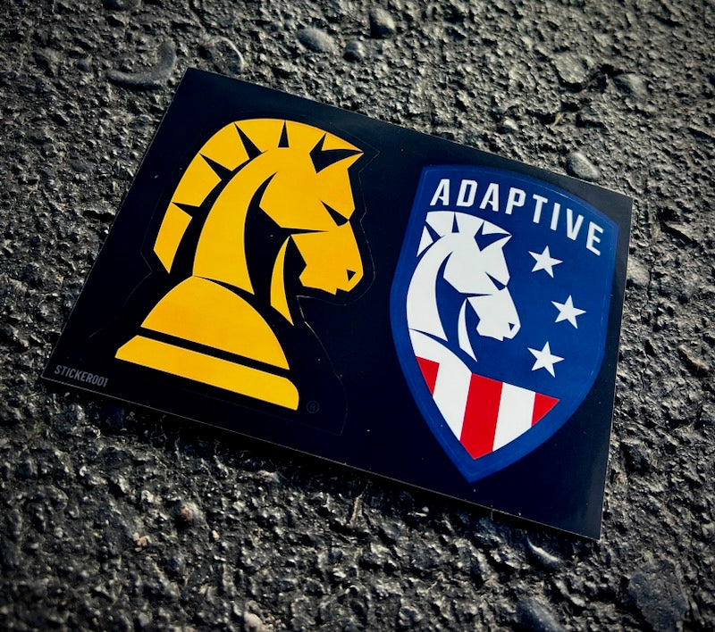 An Adaptive decal sticker sheet featuring a yellow knight emblem and a patriotic red, white, and blue shield logo on asphalt.
