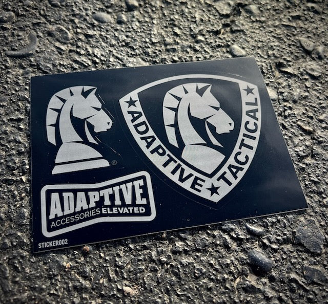 An Adaptive Tactical brand decal sticker sheet featuring knight logo graphics, resting on an asphalt surface.